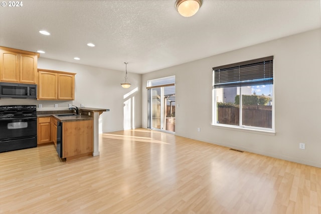 kitchen with kitchen peninsula, sink, black appliances, light hardwood / wood-style floors, and hanging light fixtures