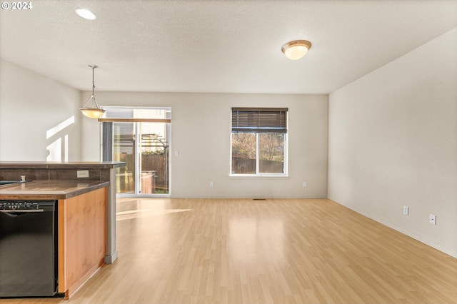 kitchen featuring a textured ceiling, hanging light fixtures, light wood-type flooring, and black dishwasher