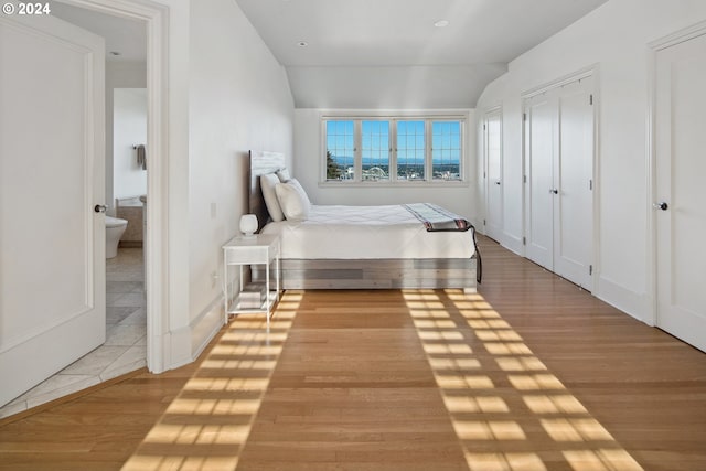 2868 NW Cumberland Rd, Portland, OR 97210 - bedroom featuring light wood finished floors, vaulted ceiling, and multiple closets