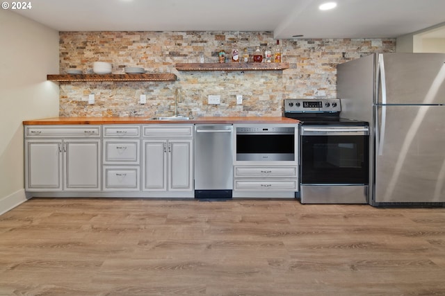 2868 NW Cumberland Rd, Portland, OR 97210 - kitchen with stainless steel appliances, tasteful backsplash, butcher block counters, light wood finished floors, and recessed lighting