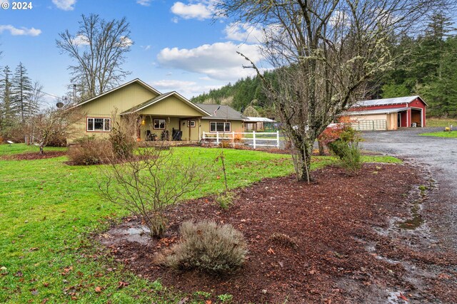 single story home featuring a garage, a porch, an outbuilding, and a front yard