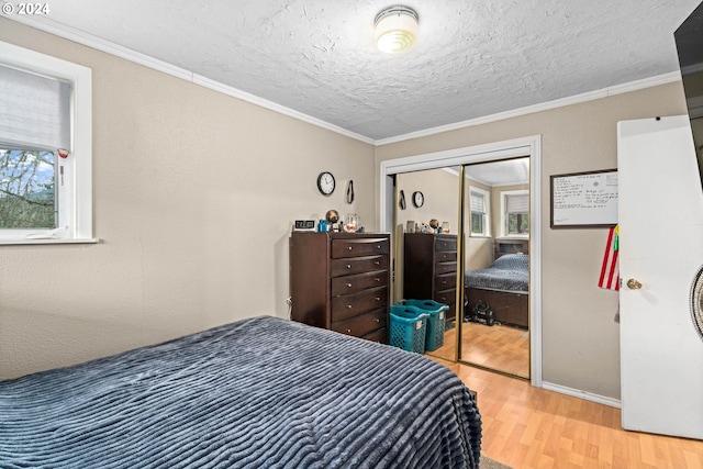 bedroom with a closet, ornamental molding, a textured ceiling, and wood finished floors