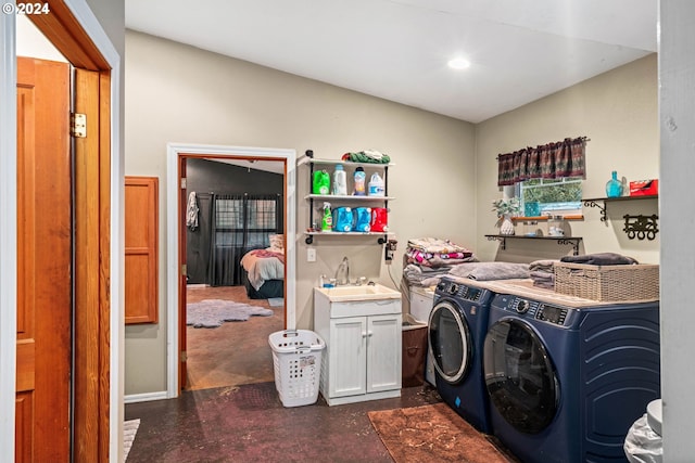 laundry room featuring washing machine and clothes dryer, cabinet space, and a sink