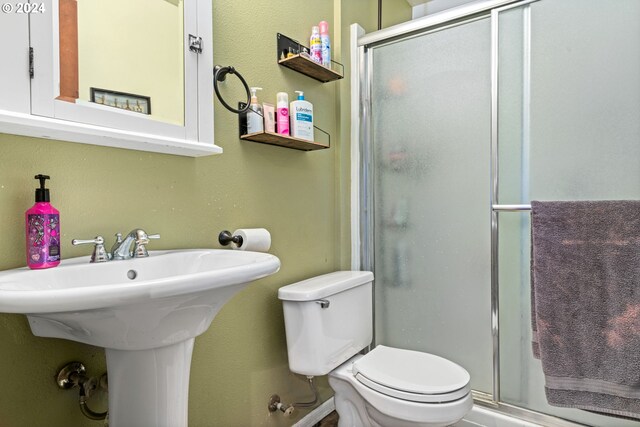 bathroom featuring walk in shower, sink, and toilet