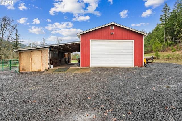 garage with gravel driveway, a detached garage, and fence