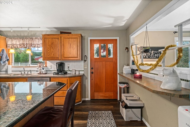 kitchen with backsplash, dark wood-type flooring, pendant lighting, brown cabinets, and a sink