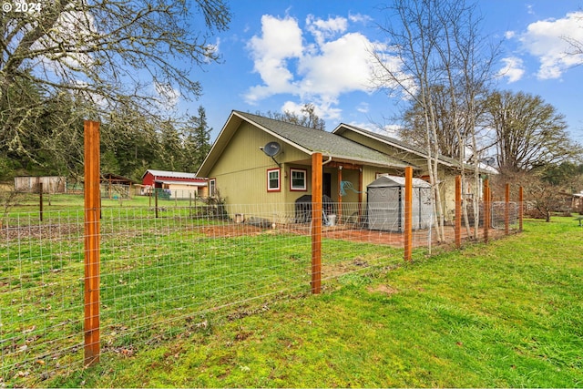 view of side of property featuring a lawn, fence, and roof with shingles