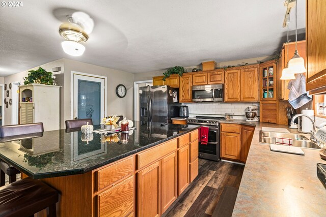 kitchen with appliances with stainless steel finishes, dark hardwood / wood-style flooring, a breakfast bar area, and a kitchen island