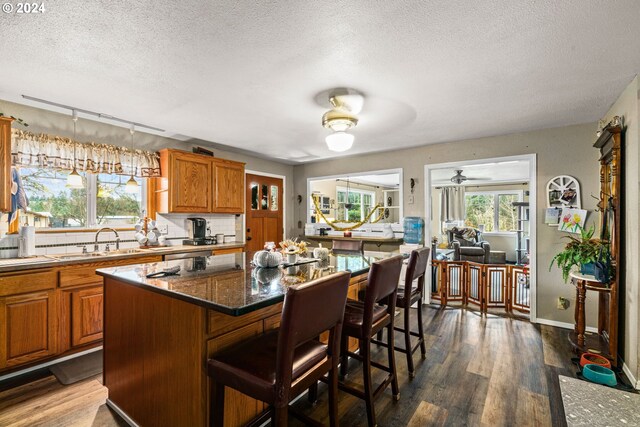 kitchen with sink, a kitchen bar, decorative backsplash, a center island, and dark wood-type flooring