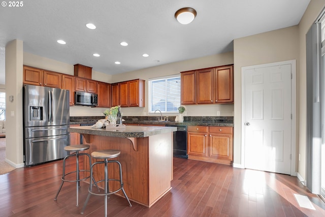 kitchen featuring sink, a breakfast bar area, a center island, appliances with stainless steel finishes, and dark hardwood / wood-style floors