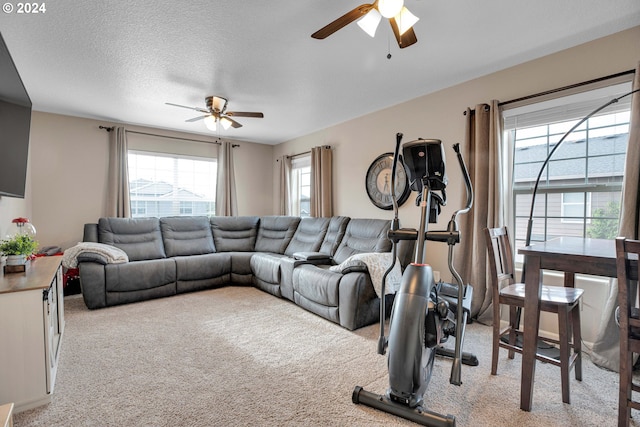 living room with light carpet, ceiling fan, and a textured ceiling