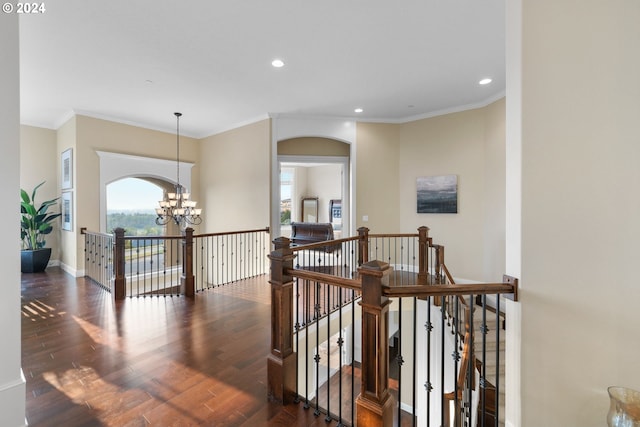 hallway with dark wood-type flooring, crown molding, and a notable chandelier