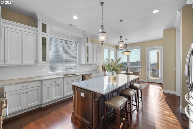 kitchen with a kitchen island, dark hardwood / wood-style flooring, light stone countertops, and white cabinetry