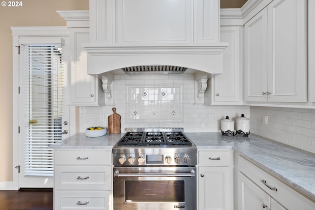 kitchen featuring dark wood-type flooring, light stone counters, white cabinetry, and stainless steel stove