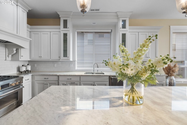 kitchen with backsplash, sink, light stone countertops, appliances with stainless steel finishes, and white cabinets