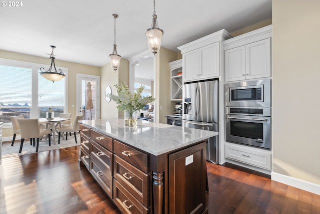 kitchen featuring stainless steel appliances, dark hardwood / wood-style flooring, light stone counters, a center island, and white cabinets