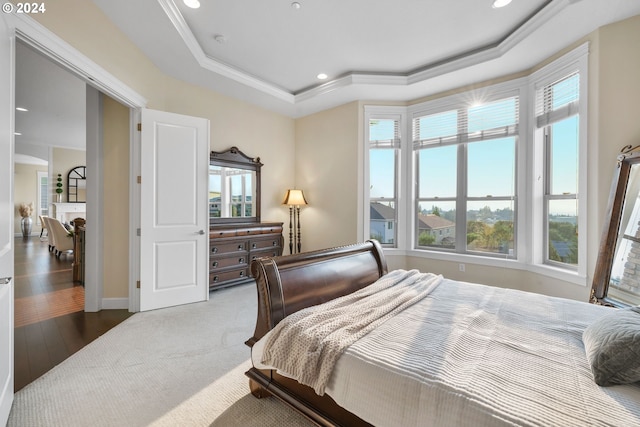 bedroom with crown molding, multiple windows, hardwood / wood-style flooring, and a tray ceiling