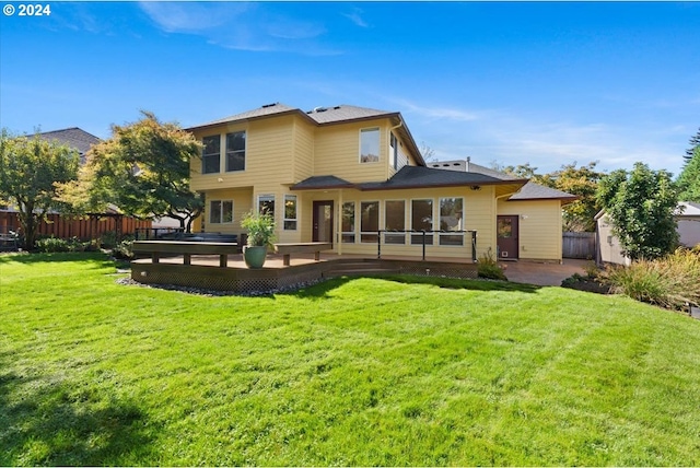 rear view of property featuring a lawn and a deck