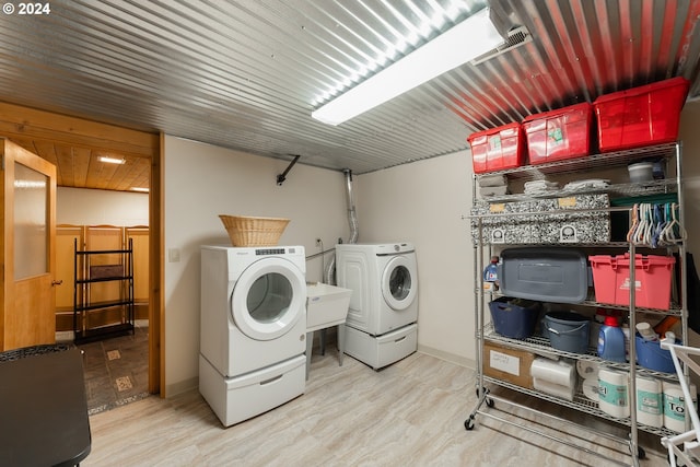 washroom with hardwood / wood-style flooring, washer and dryer, and sink