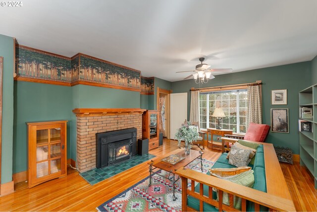 living room with hardwood / wood-style floors, a brick fireplace, and ceiling fan