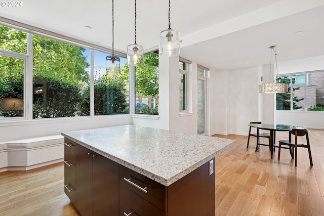 kitchen featuring a center island, dark brown cabinetry, light wood-type flooring, and a healthy amount of sunlight