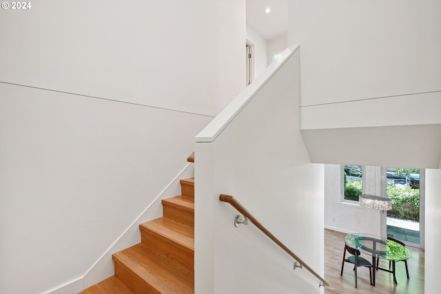 staircase with hardwood / wood-style flooring and a notable chandelier