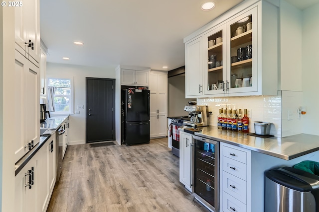 kitchen featuring stainless steel electric stove, white cabinets, black refrigerator, tasteful backsplash, and wine cooler