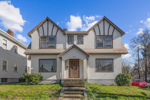 tudor-style house featuring a front lawn