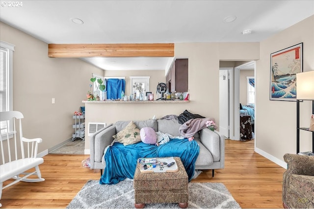 living room featuring beamed ceiling and light hardwood / wood-style floors