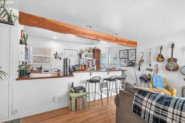 kitchen with a breakfast bar area, kitchen peninsula, light hardwood / wood-style flooring, and white appliances