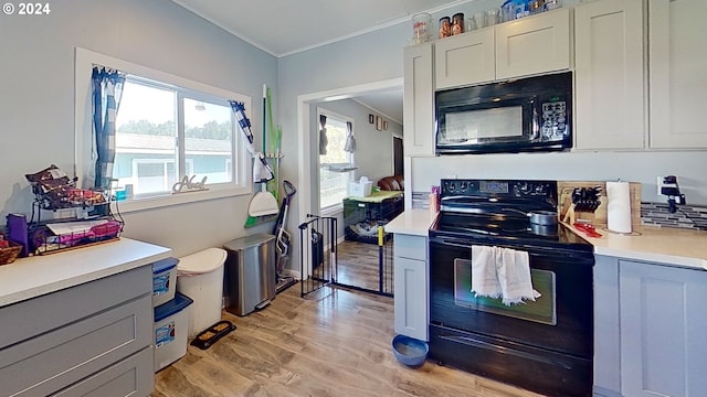 kitchen featuring white cabinetry, gray cabinetry, black appliances, crown molding, and light hardwood / wood-style flooring