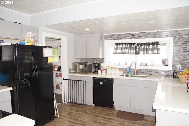 kitchen featuring wood-type flooring, sink, backsplash, and black appliances