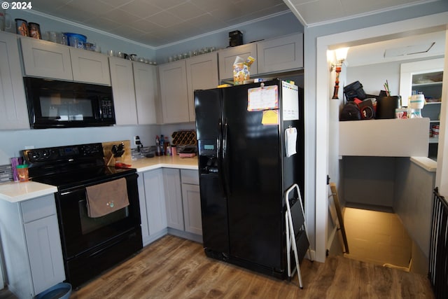 kitchen with hardwood / wood-style flooring, ornamental molding, gray cabinets, and black appliances