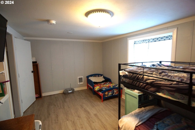 bedroom featuring crown molding and light wood-type flooring