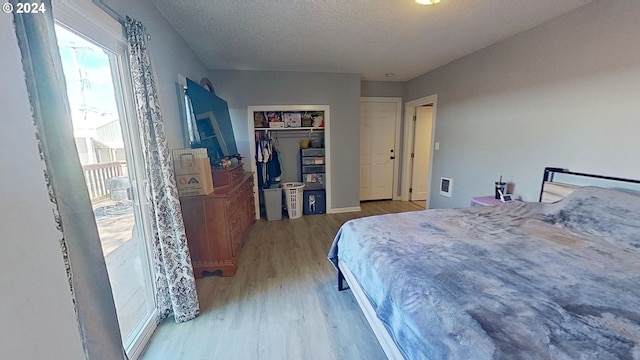 bedroom with a closet, light hardwood / wood-style flooring, and a textured ceiling