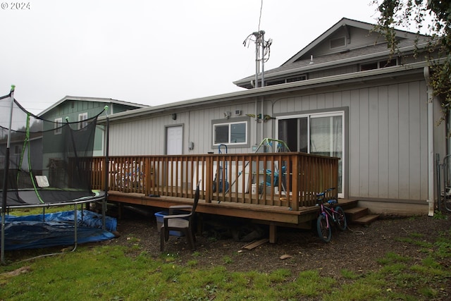 back of house featuring a wooden deck and a trampoline