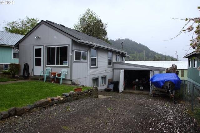 back of property featuring a mountain view, a garage, and a lawn