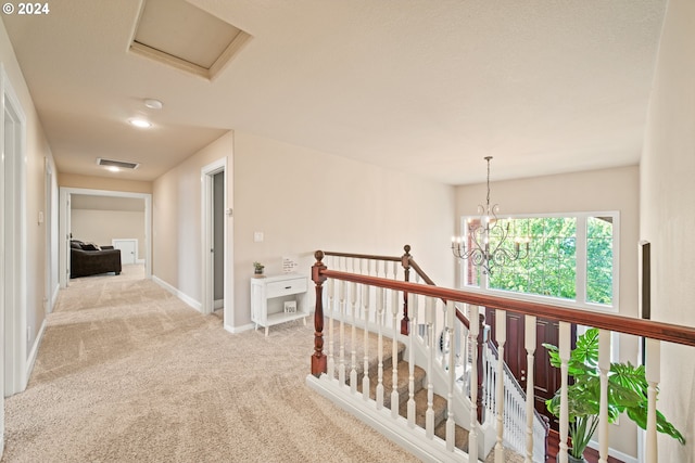 hall with light colored carpet and a notable chandelier