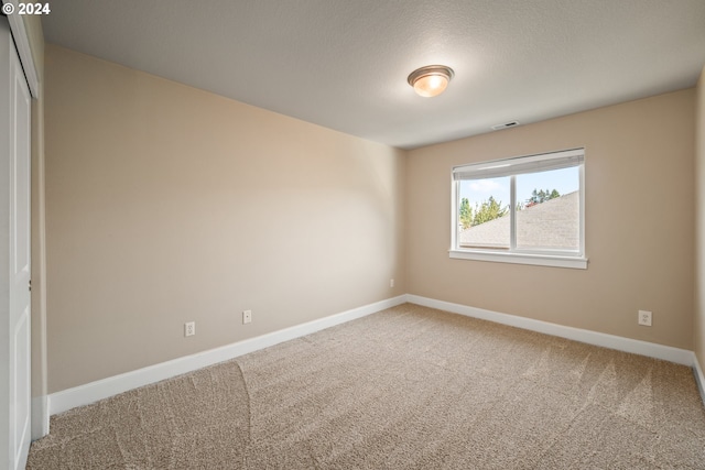 carpeted empty room with a textured ceiling