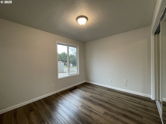 unfurnished room with dark hardwood / wood-style flooring and a textured ceiling