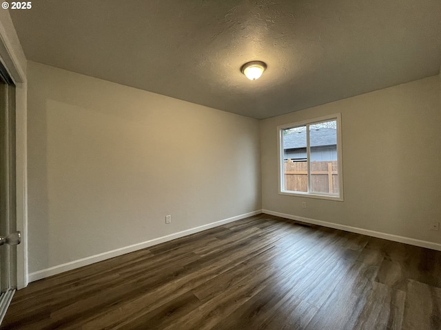 unfurnished room with a textured ceiling and dark hardwood / wood-style flooring