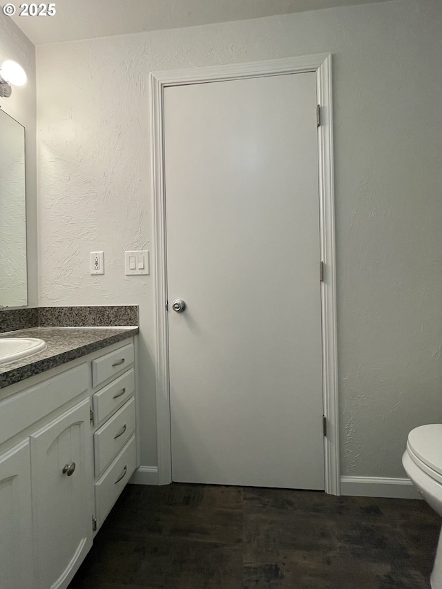 bathroom featuring toilet, vanity, and wood-type flooring