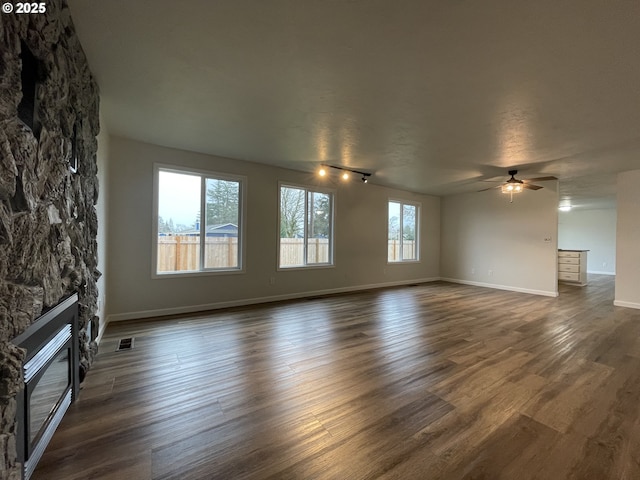 unfurnished living room with ceiling fan, a fireplace, dark hardwood / wood-style flooring, and a textured ceiling