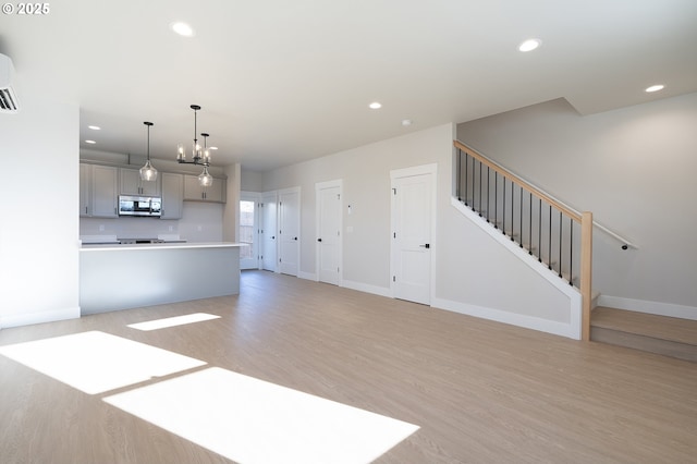 unfurnished living room featuring a notable chandelier and light wood-type flooring