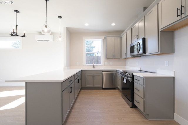 kitchen with pendant lighting, sink, kitchen peninsula, stainless steel appliances, and light hardwood / wood-style flooring