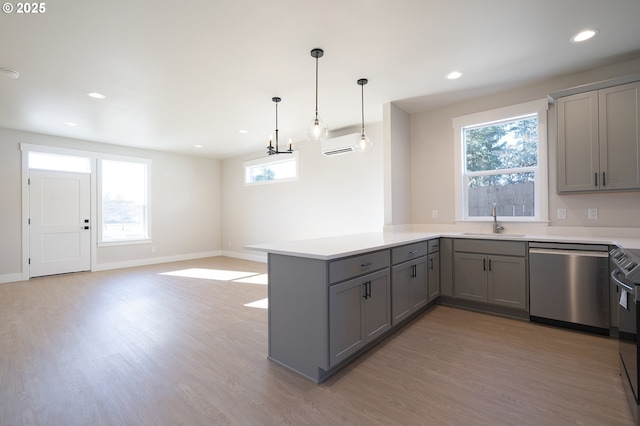 kitchen with decorative light fixtures, sink, stainless steel dishwasher, kitchen peninsula, and light hardwood / wood-style flooring