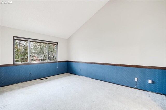 unfurnished room featuring light carpet and vaulted ceiling