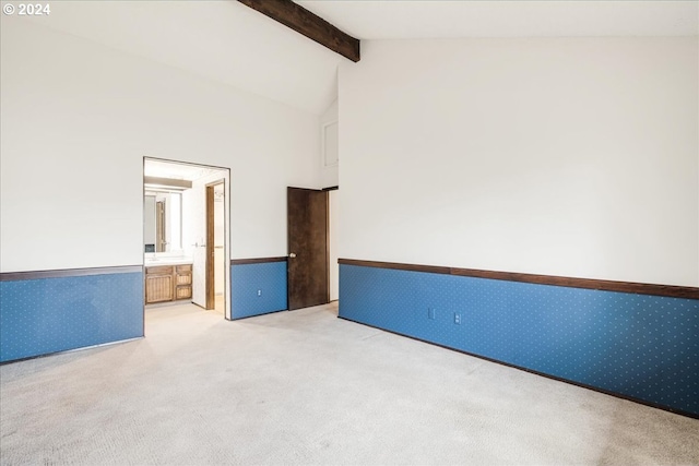 unfurnished room featuring light colored carpet and lofted ceiling with beams