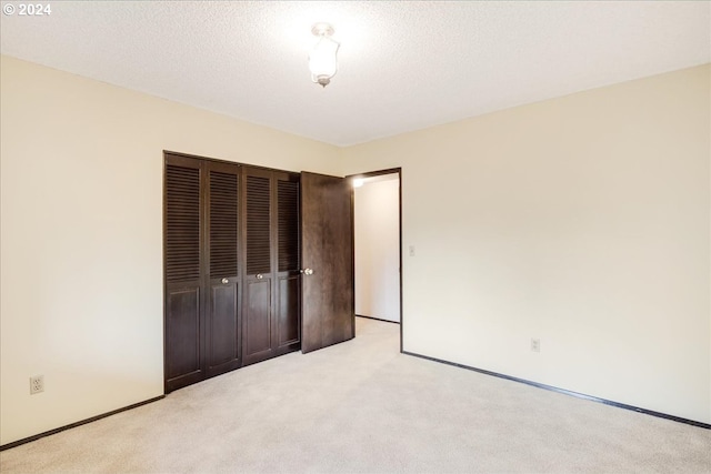 unfurnished bedroom featuring light carpet, a textured ceiling, and a closet