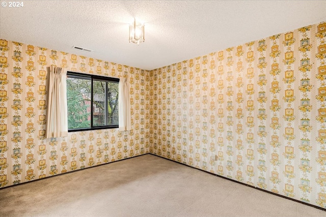 carpeted empty room featuring a textured ceiling